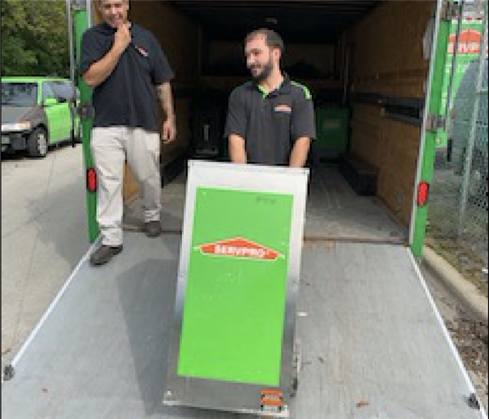 Two SERVPRO members loading the truck with equipment.