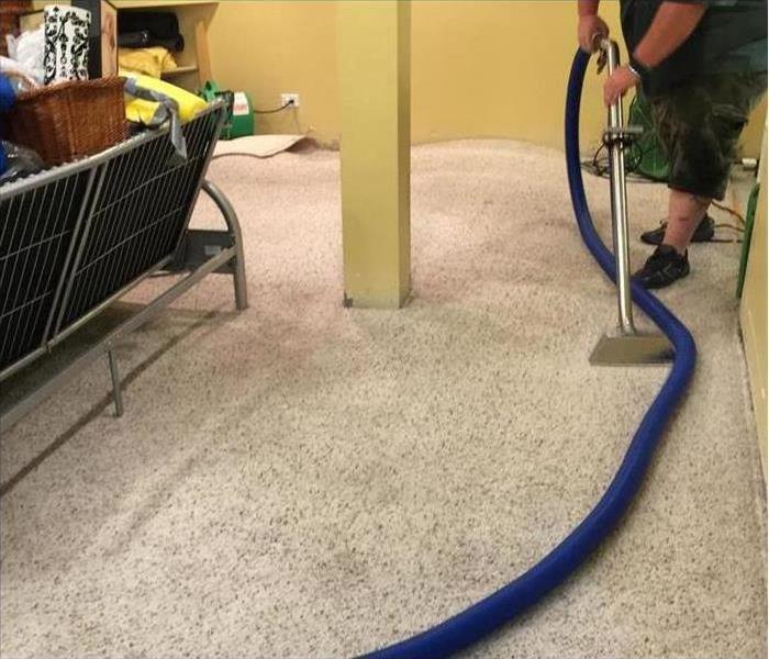 Someone extracting water from a carpet in a home