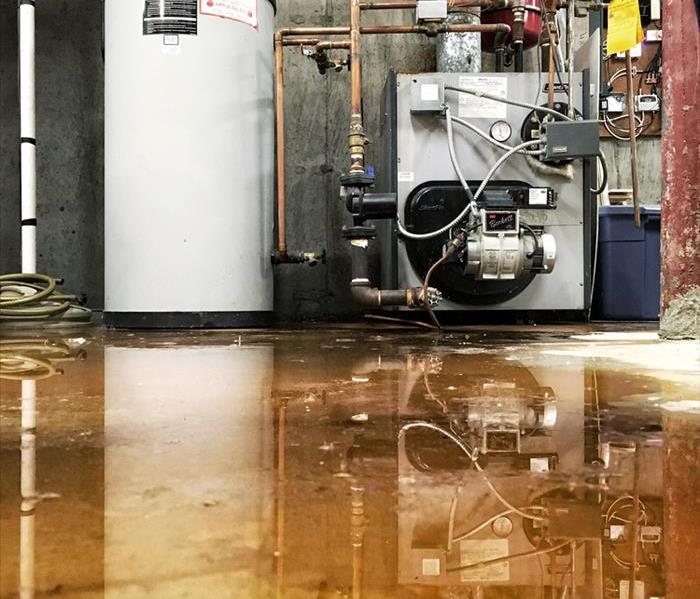 A burst pipe at the furnace and water tank has caused a leak on the basement floor of a house